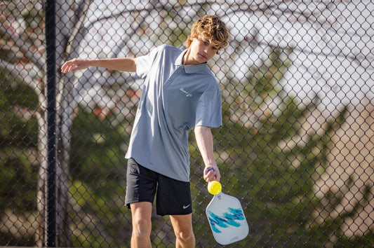 Pickleball player focusing on the ball mid-swing, demonstrating improved hand-eye coordination on a sunny outdoor court