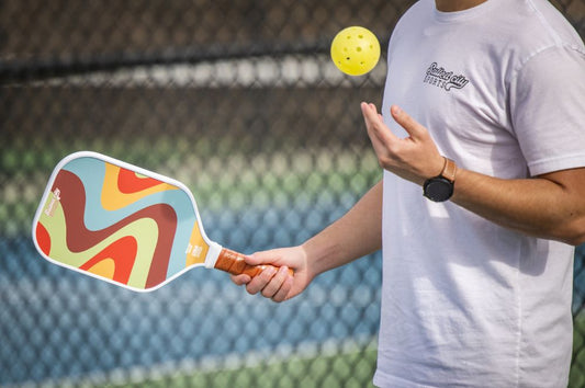 Pickleball player tossing a ball in the air with paddle ready to serve—illustrating preparation and focus to improve pickleball reflexes