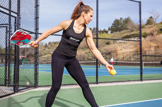 Pickleball player tossing a ball in the air mid-game, demonstrating stamina and athleticism for pickleball fitness tips and endurance training.