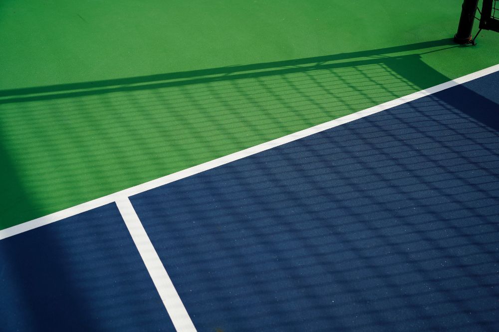 A tennis court featuring blue and green surfaces, illustrating the evolution of sports like pickleball rules.