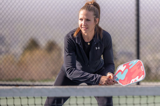 A woman focuses on her pickleball opponent while implementing singles pickleball strategies.