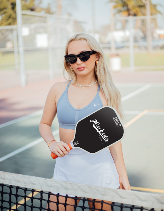 Woman holding a customized pickleball paddle on a court