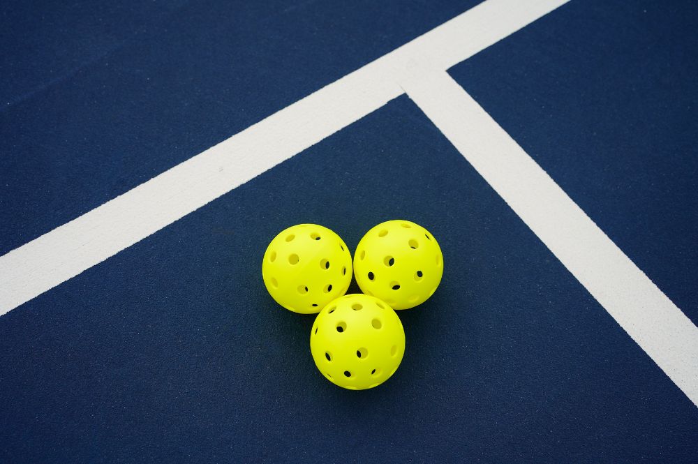 Pickleball balls on a court, showcasing a vibrant home pickleball setup in the background.