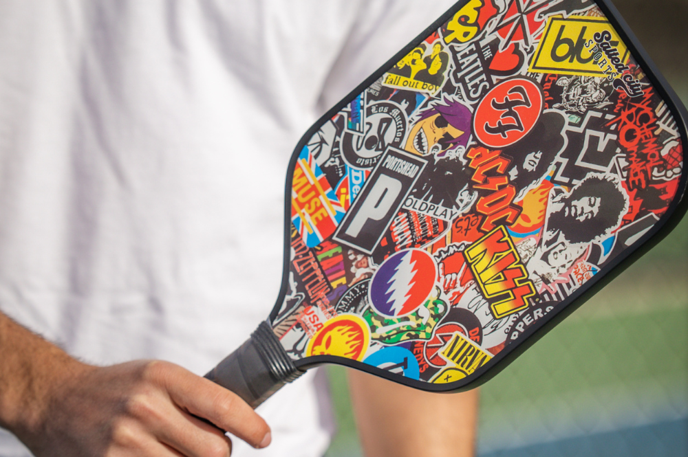 Beginner-friendly paddle held by woman, blue and white design. "How To Choose A Pickleball Paddle For Beginners With Salted City Sports.