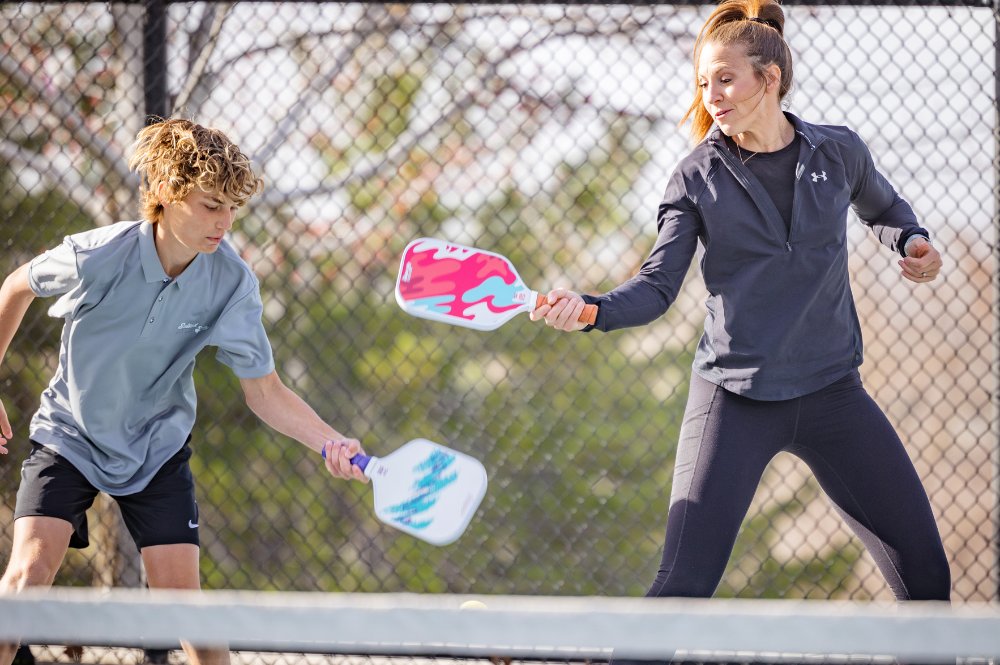 Two family members playing pickleball showing the camaraderie of pickleball for families.