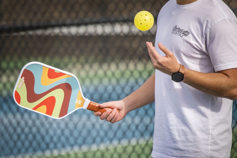 Pickleball player tossing a ball in the air with paddle ready to serve—illustrating preparation and focus to improve pickleball reflexes