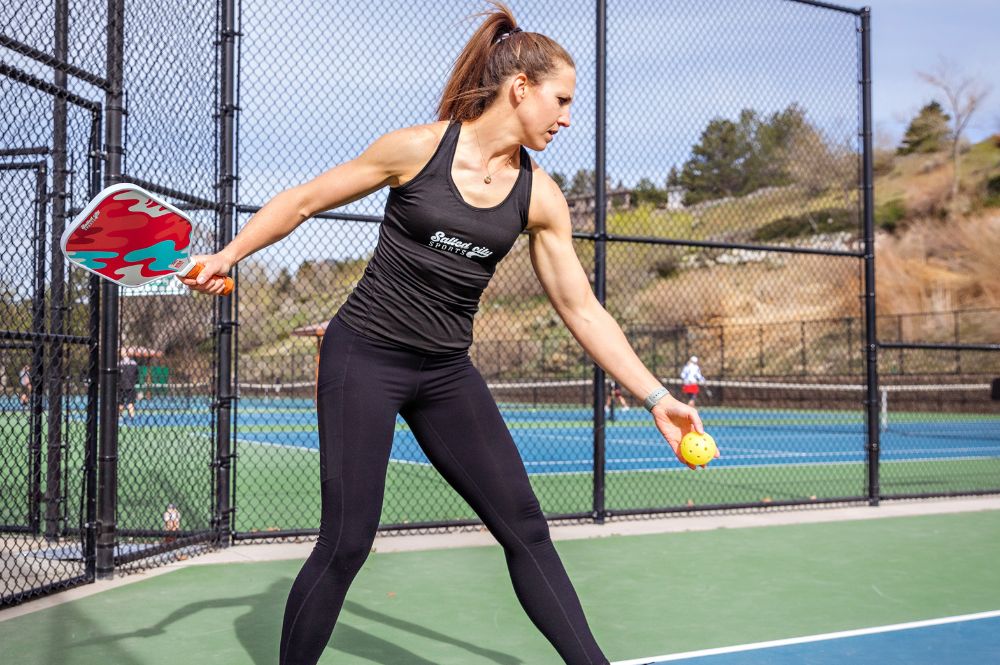 Pickleball player tossing a ball in the air mid-game, demonstrating stamina and athleticism for pickleball fitness tips and endurance training.