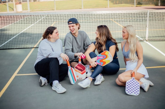 A group of four young individuals laughing together showing the benefits of pickleball mental health.