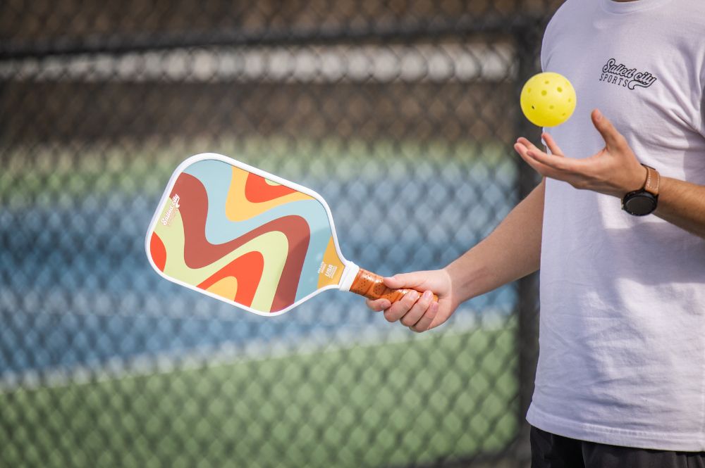   A pickleball player at pickleball practice about to serve the ball. 