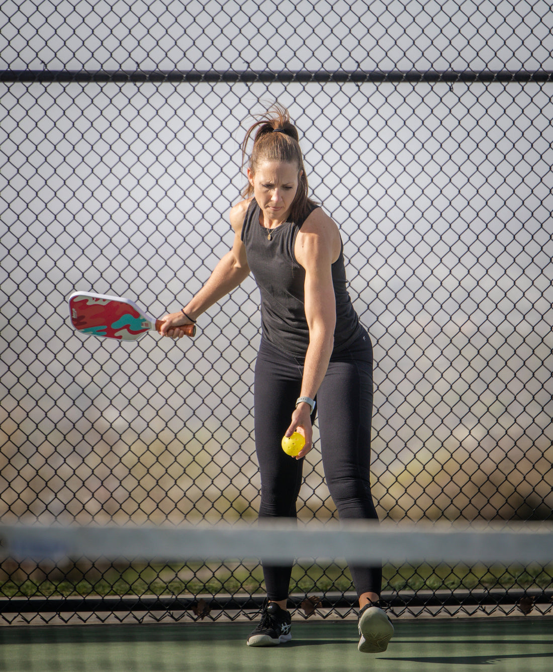 Pickleball player serving first on a court