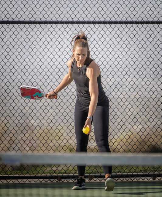 Pickleball player serving first on a court