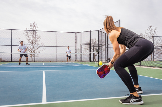 A woman holding a paddle hitting the ball to her opponents. Explore the Best Pickleball Paddle Materials.