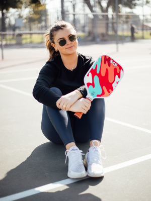 Pickleball Player holding a pickleball paddle on a court.