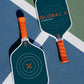 Two branded pickleball paddles with the GlobalX logo with orange handles on a blue and green court surface.